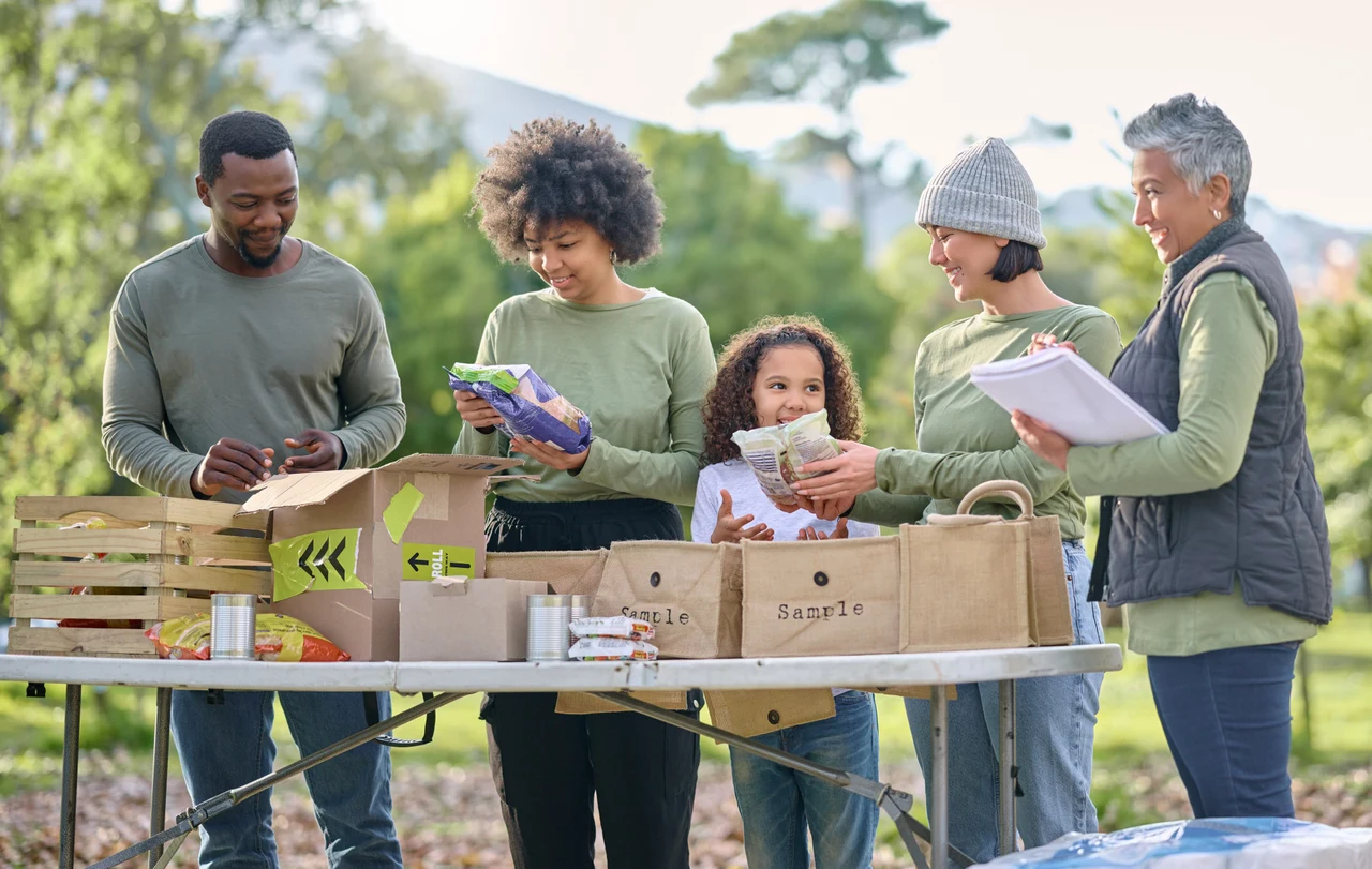 Diverse group of volunteers packing grocery bags at an outdoor community food drive