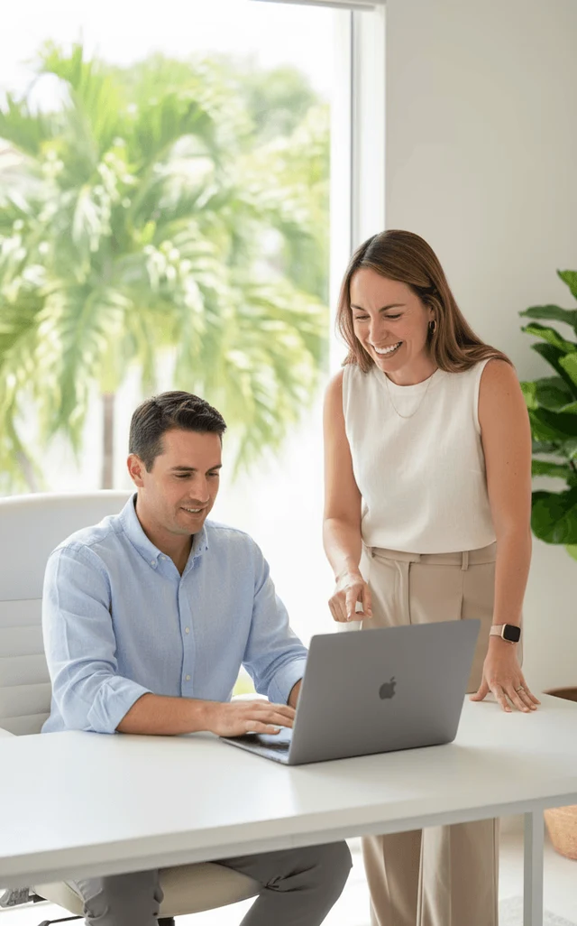 Two Palm Consulting consultants reviewing a Salesforce setup on a laptop in the West Palm Beach office