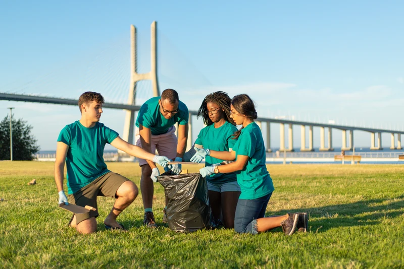 Volunteers in matching shirts collecting litter in a park during a community cleanup