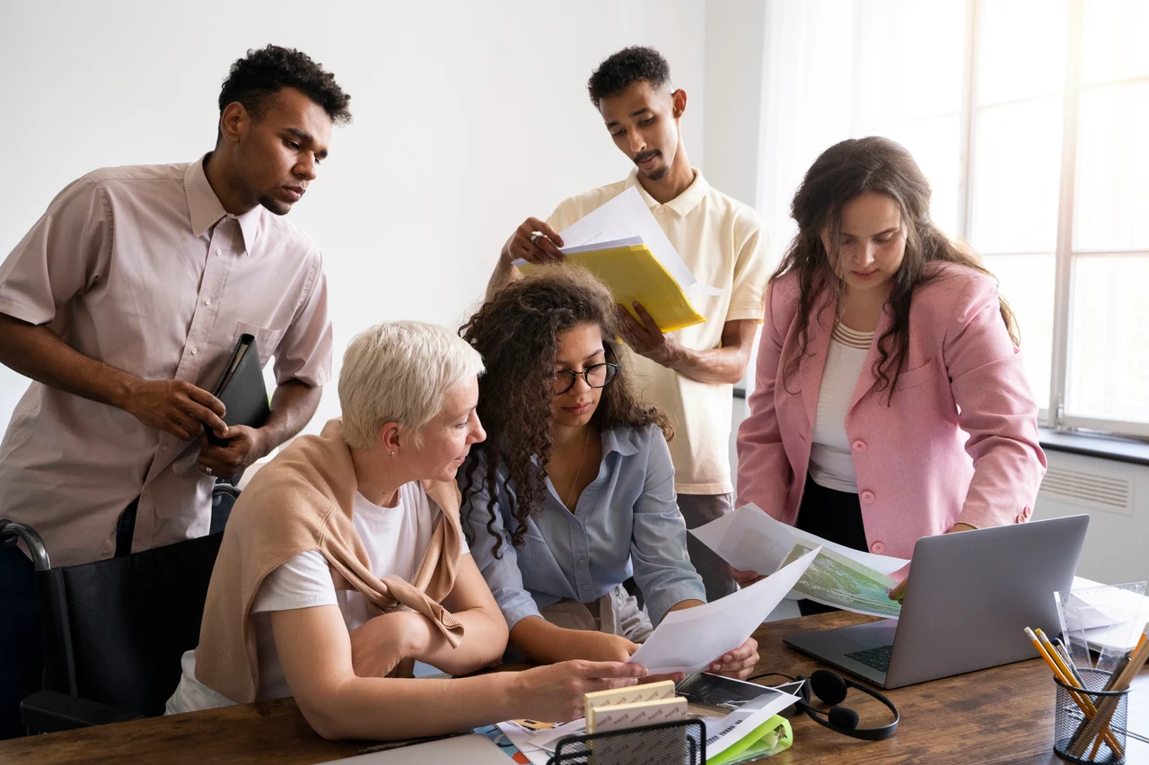 Diverse nonprofit team reviewing reports and data around a laptop in an office